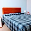 Camera da letto con letto matrimoniale e copriletto a quadri blu e bianchi.