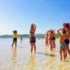 Persone in acqua al mare, con braccia sollevate.