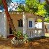 Una casa bianca immersa nel verde, con veranda e sedie a sdraio.